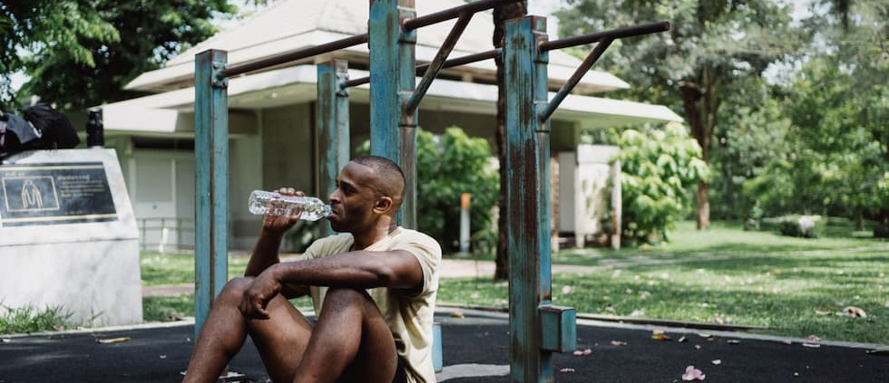 man-sitting-on-pavement-while-drinking-water